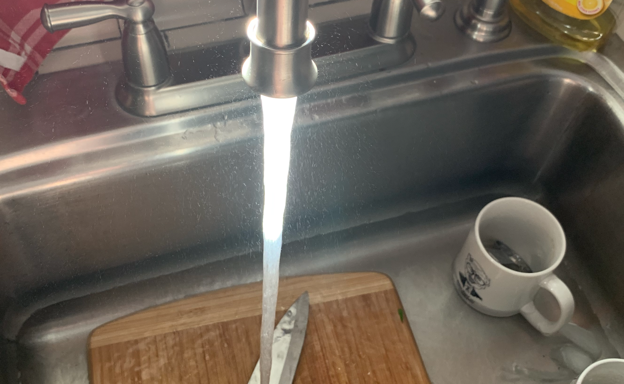 Water droplets into a sink on knife cutting board